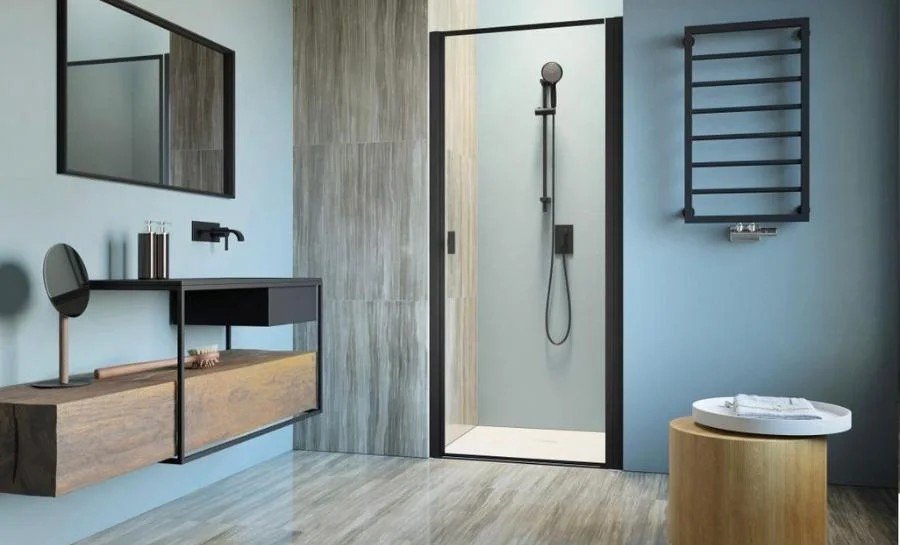 Baño con paredes azules, mampara negra y toallero eléctrico