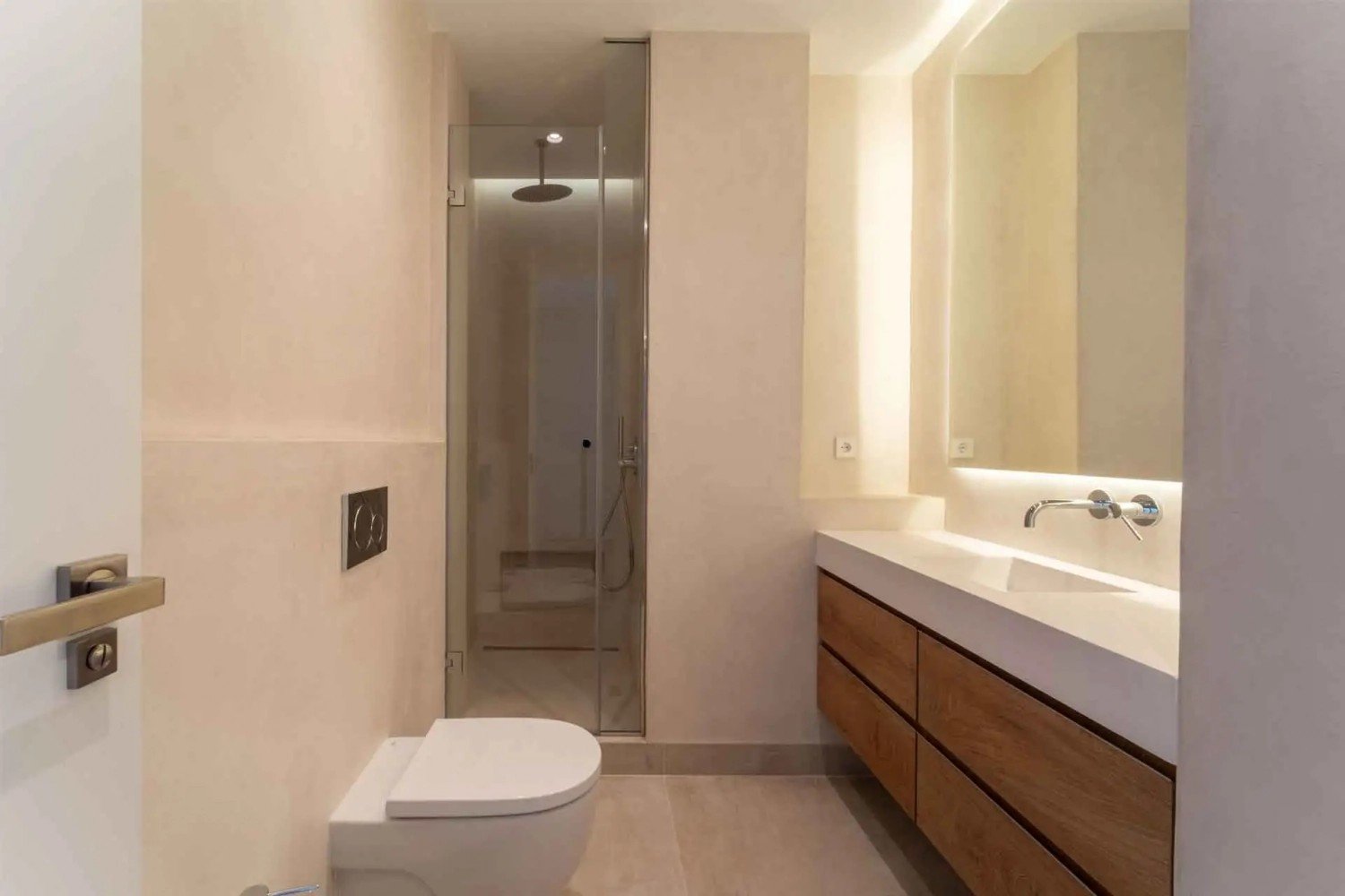 Baño reformado en tonos beige con ducha de cristal y mueble de madera